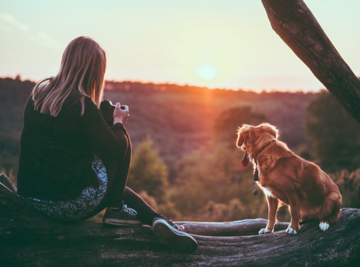 Mujer rubia con su perrito viendo el atardecer