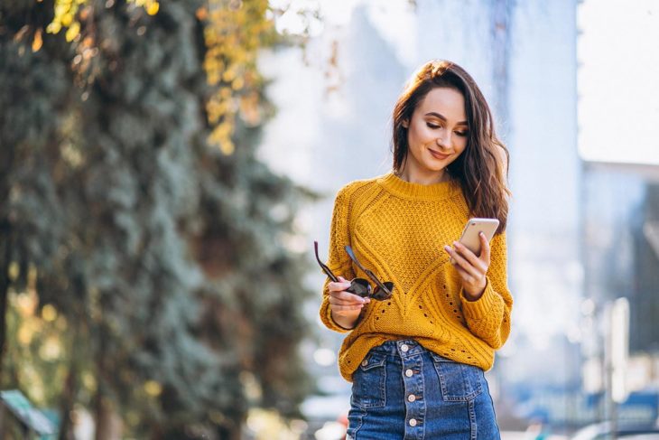 Mujer viendo su celular mientras camina