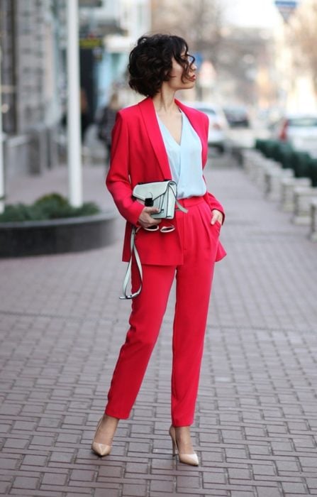 Chica usando un traje rojo, blusa blanca y bolso chico