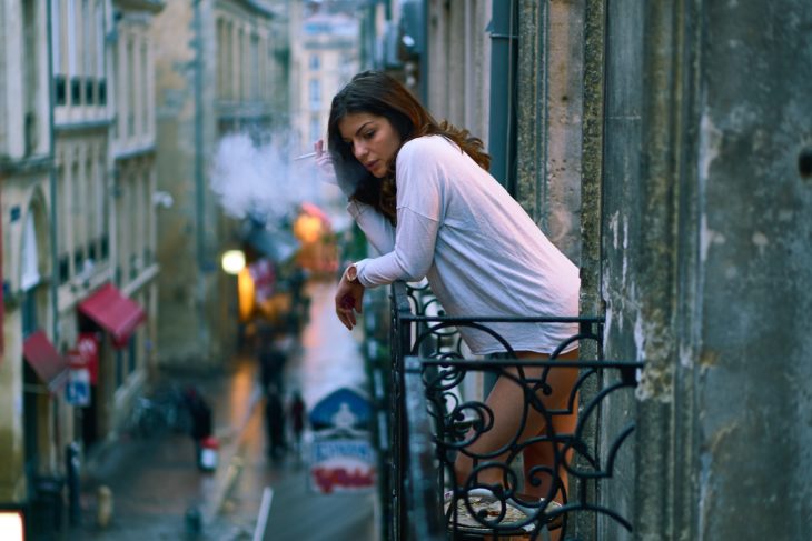 Mujer fumándose un cigarrillo en la terraza de la habitación