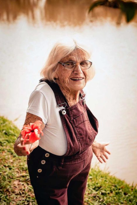 Claire V. a la orilla de un lago muestra una flor