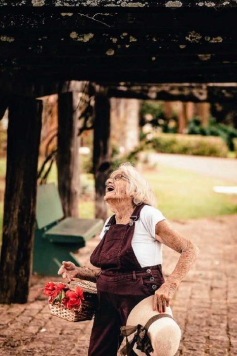 Claire V. una mujer de 90 años camina por un parque con una canasta de flores y ríe a carcajadas