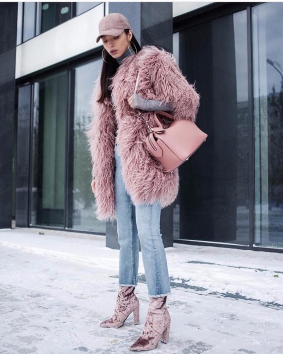 Chica usando un abrigo afelpado de color rosa, botas y gorra 
