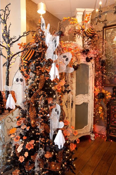 Pino navideño con ramas oscuras con decoración de fantasmas y calabazas