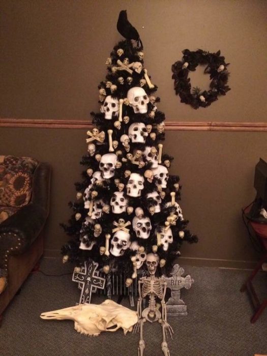 Pino de Navidad con ramas oscuras, accesorios de calaveras, velas blancas y luces