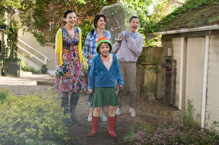 tres mujeres y una niña en un jardín se ríen de algo