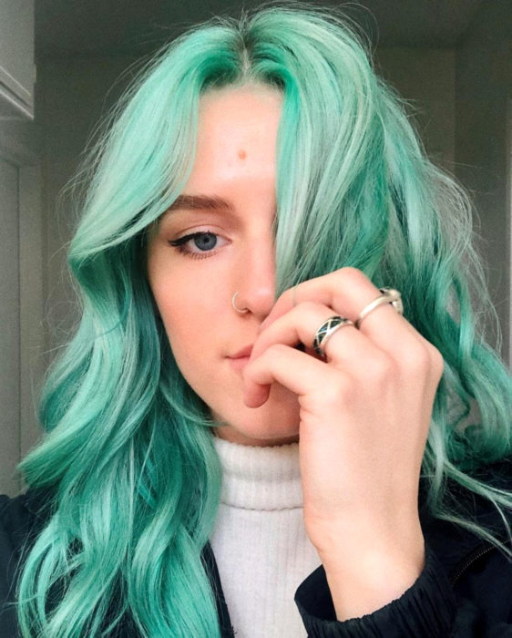 Tinte color verde menta; chica de cabello largo y ondulado con piercing en la nariz