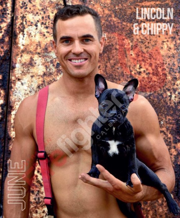 Calendario de bomberos australianos con animales; hombre sonriendo y cargando perro bulldog francés negro con el pecho blanco