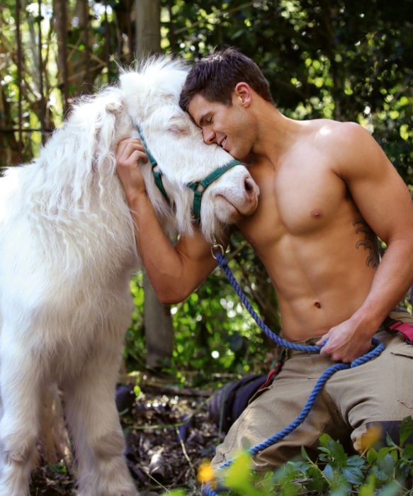 Calendario de bomberos australianos con animales; hombre con tatuajes abrazando a un pony blanco