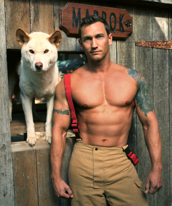 Calendario de bomberos australianos con animales; hombre con tatuajes en los brazos y un perro blanco