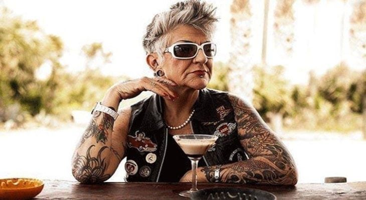 Abuela conbrazos tatuados bebiendo en un bar