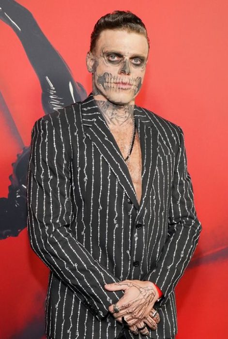 Gus Kenworthy usando un traje a rayas negro con blanco y una pintura en el rostro de calavera 