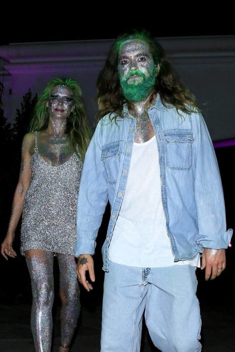 Heidi Klum y Tom Kaulitz caminando tomados de las manos mientras muestran sus disfraces de Halloween cubiertos de brillantina 