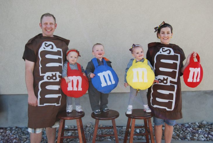 Familia con disfraces de empaques de M&m's 