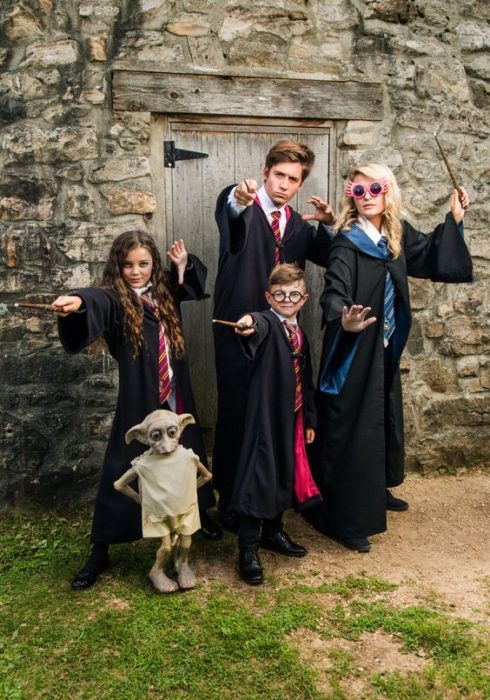 Familia vestida con capas largas y pscuras con diseños de Harry Potter 