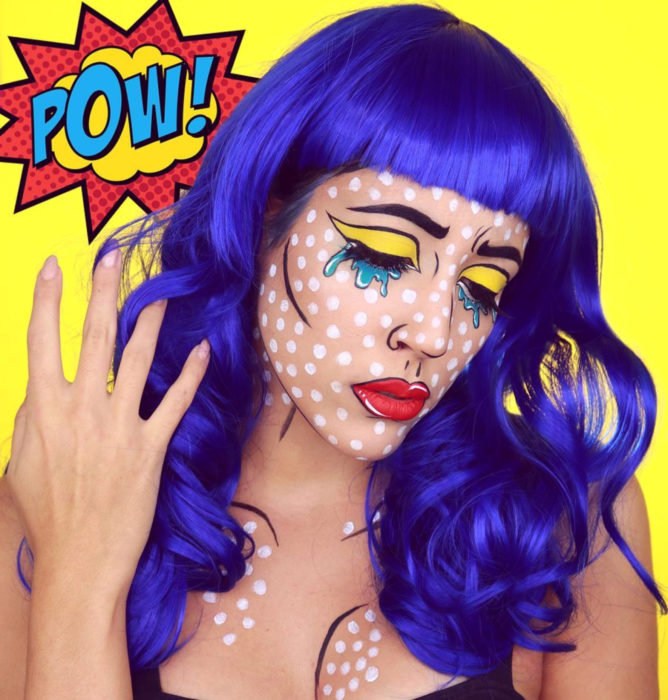 Disfraz de Halloween de comic pop art; chica con peluca azul con peinado ondulado y fleco, maquillada estilo historieta con puntos blancos, sombra amarilla y lágrimas azules