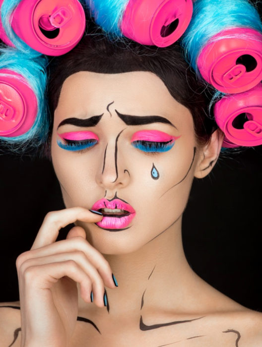 Disfraz de Halloween de comic pop art; mujer maquillada estilo historieta con sombra de ojos fosforescente, lágrimas y latas de refresco como tubos para el cabello