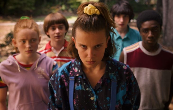 Elenco de Stranger Things con ropa de la década de los 80 enfrentándose al Demogorgo 