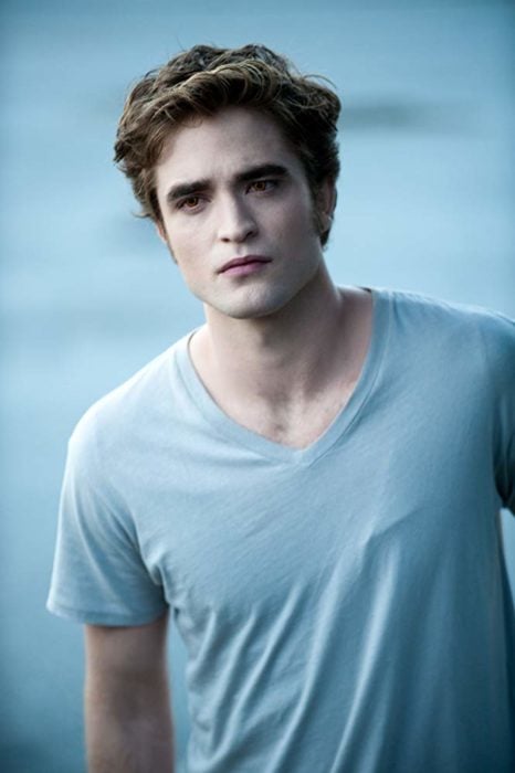 Edward Cullen usando una playera azul mientras está parado viendo a Bella 