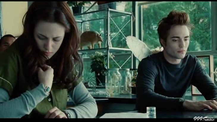 Bella oliendo su camisa mientras Edward Cullen la observa con cara de asco 