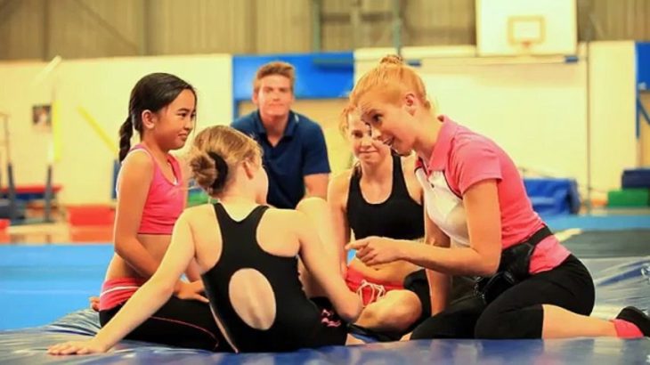 un grupo de gimnastas sentadas sobre el piso platicando