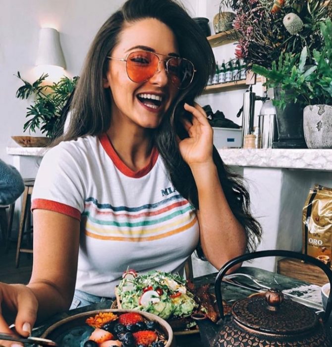 Chica sentada frente a un plato de ensalada y comiendo de manera saludable 