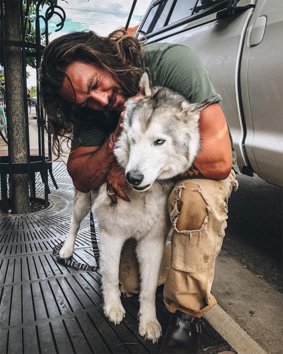 Jason Momoa abrazando a un perro husky