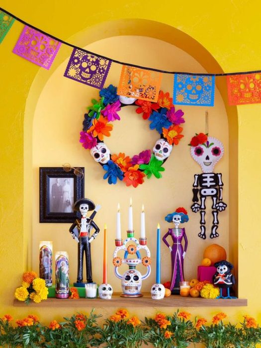 Altar de muertos decorados con papel picado, calaveritas de azúcar y catrinas de papel 