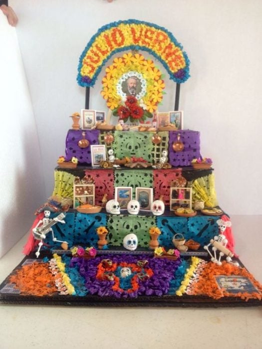 Altar de muertos decorados con papel picado, calaveritas de azúcar y catrinas de papel 