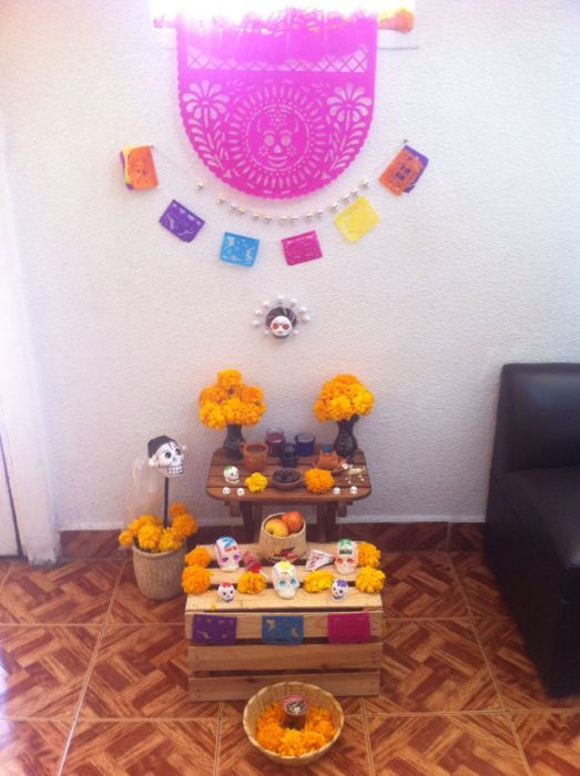 Altar de muertos decorados con papel picado, calaveritas de azúcar y catrinas de papel 