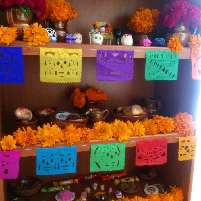 Altar de muertos decorados con papel picado, calaveritas de azúcar y catrinas de papel 