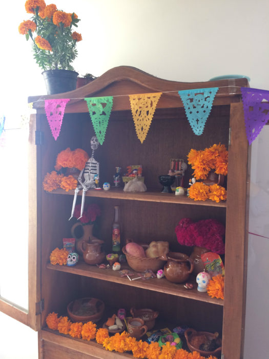 Altar de muertos decorados con papel picado, calaveritas de azúcar y catrinas de papel 