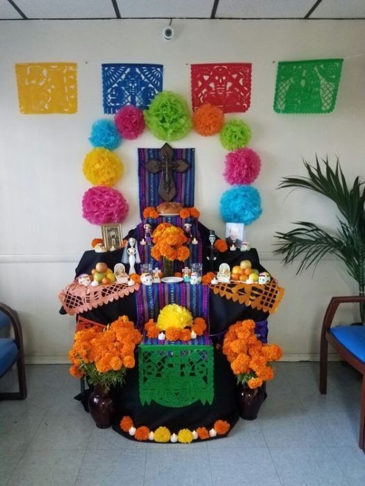 Altar de muertos decorados con papel picado, calaveritas de azúcar y catrinas de papel 