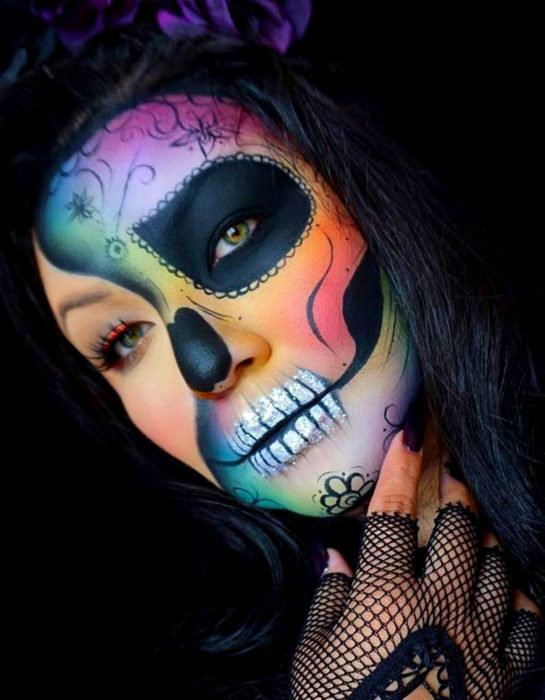 Maquillaje moderno de Catrina de Día de Muertos de colores del arcoíris, verde, azul, morado, rosa, anaranjado y rojo, con guantes de tela de red