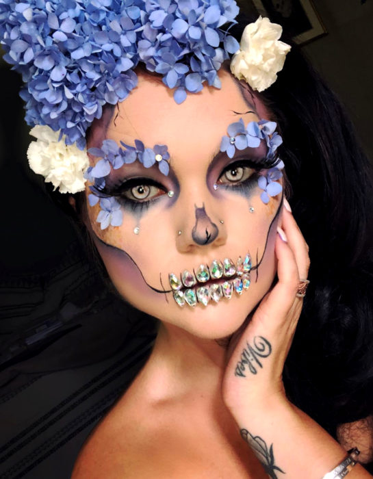 Maquillaje moderno de Catrina de Día de Muertos con flores hortensias en la cabeza y alrededor del ojo