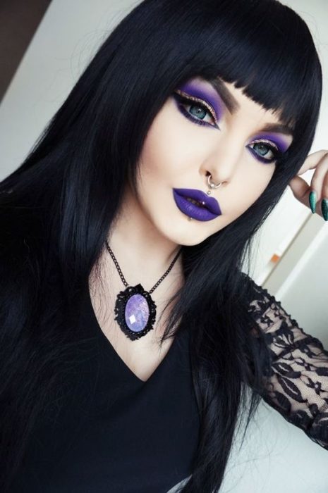 Chica llevando maquillaje inspirado en bruja con tonos morados