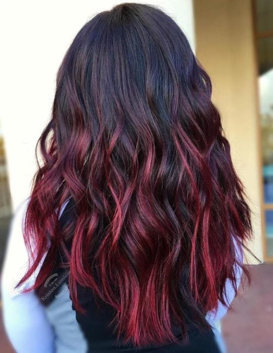 Chica mostrando su cabello con mechas de color rojo