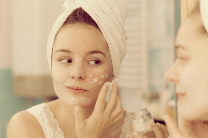 Mujer aplicándose crema en el rostro luego de una ducha