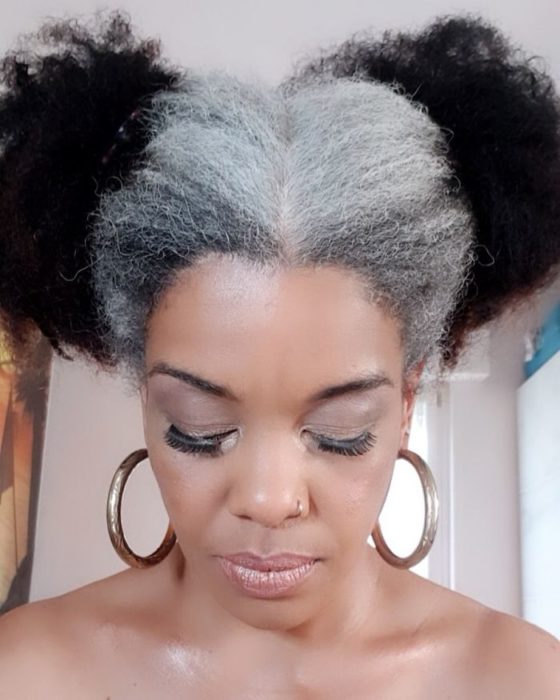 Mujer afroamericana mostrando su cabello mitad canoso mitad de color negro 