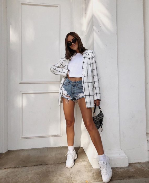 Chica usando shorts con un top blanco, blazer y tenis fila de color blanco 