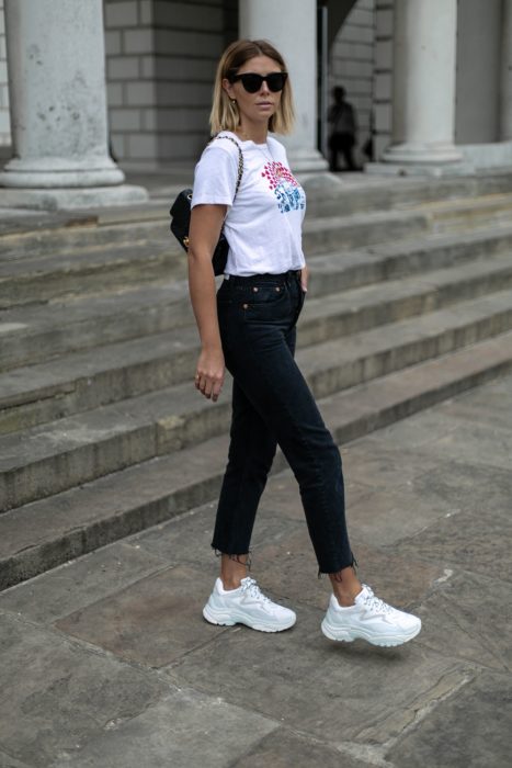 Chica usando un pantalón negro con una blusa y tenis fila de color balncos 