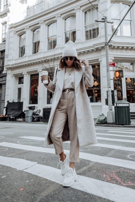 Chica usando un conjunto de color beige con abrigo y gorro con unos tenis fila de color blanco 