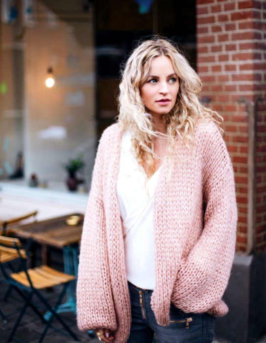 Oversized cardigan; mujer de cabello rubio y ondulado con suéter tejido holgado color rosa