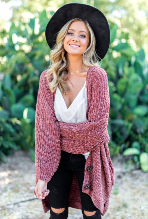 Oversized cardigan; chica rubia de ojos grises, con sombrero negro y suéter holgado rosa