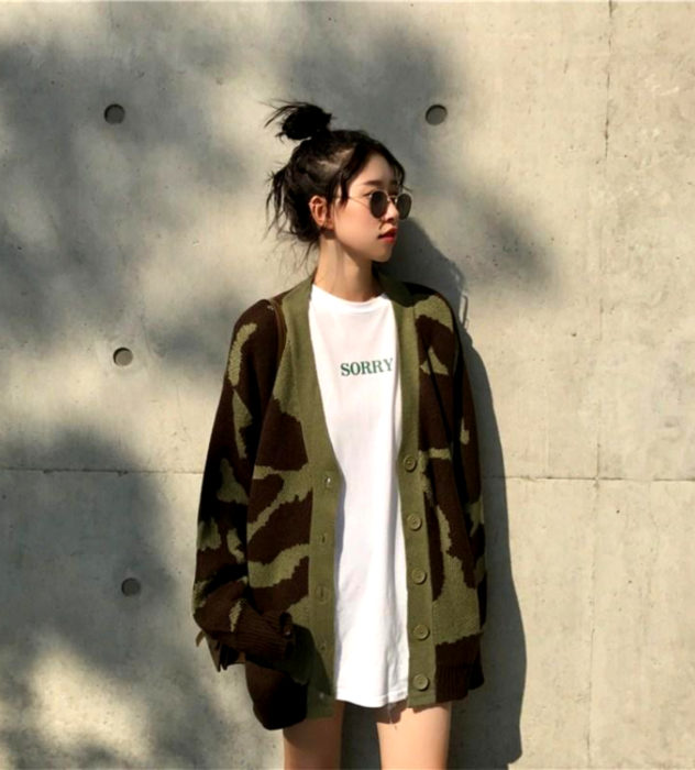 Oversized cardigan; chica coreana con peinado de chongo alto, con lentes de sol y suéter holgado con estampado de camuflaje café y verde