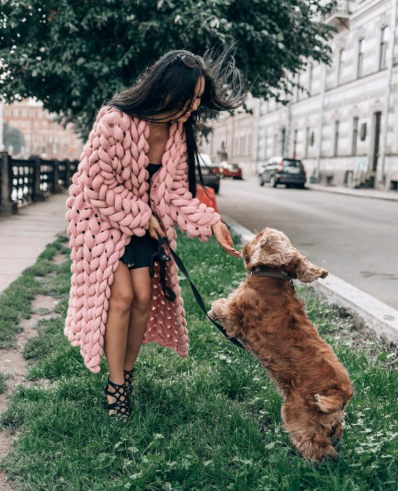 Oversized cardigan; chica con suéter holgado de crochet grueso color rosa, con su perro cocker spaniel café