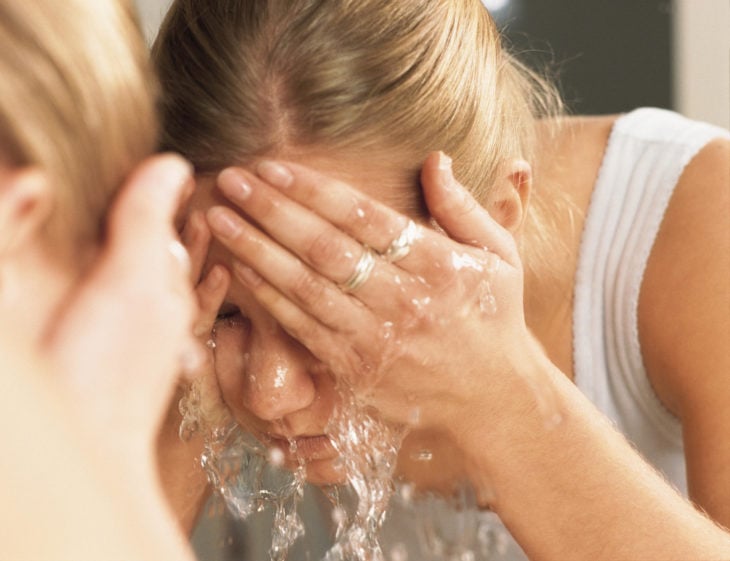 Chica lavando su rostro para eliminar maquillaje e impuresas