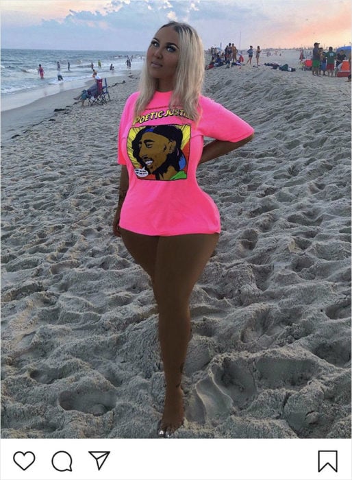 Chica usando una camiseta de color rosa mientras posa para una fotografía en la playa