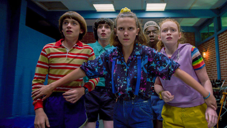 Grupo de niños asustados, usando ropa de los 80, escena de la serie Stranger Things 