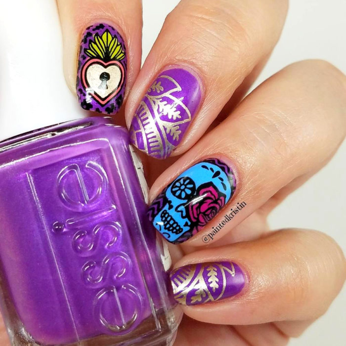 Manicura de Día de Muertos; uñas largas cuadradas pintadas con esmalte morado con diseño de cráneo, con flores y corazón